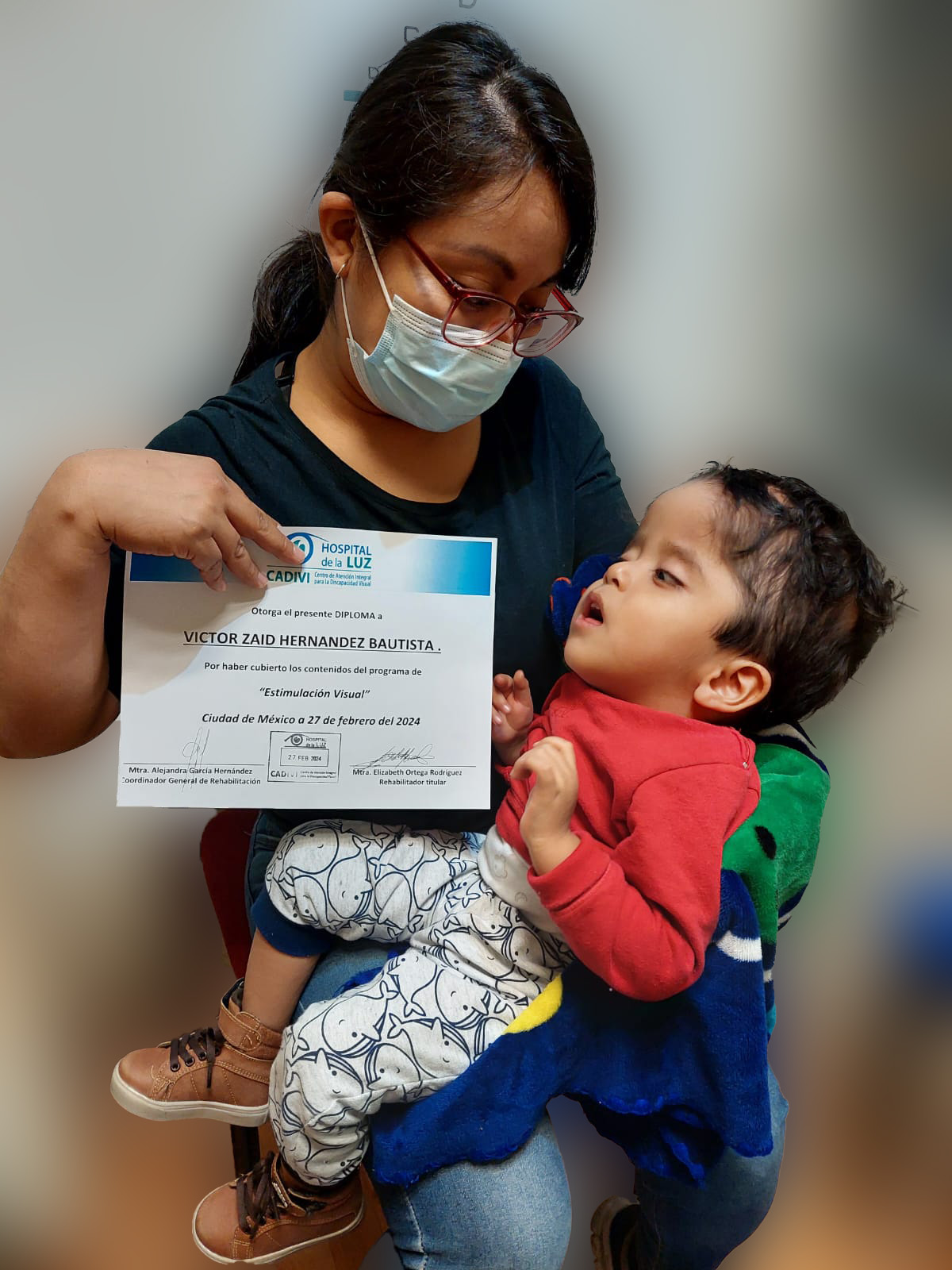 Señora con su hijo sosteniendo un reconocimiento frente a la cámara